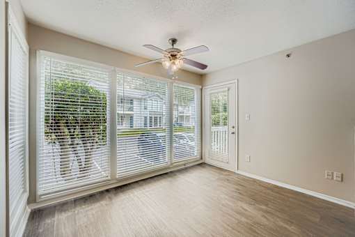A room with a ceiling fan and sliding glass doors.