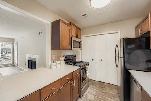 A kitchen with brown cabinets and a black refrigerator.