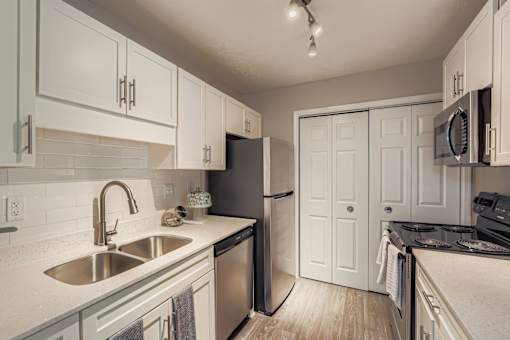 A kitchen with white cabinets and a black refrigerator.