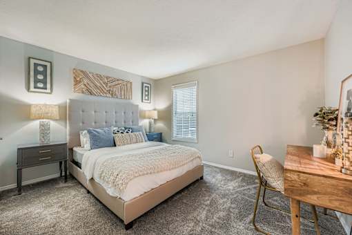 A bedroom with a large bed, a chair, and a table.