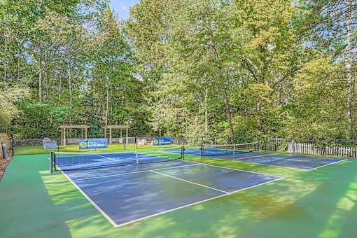 A tennis court surrounded by trees and a fence.