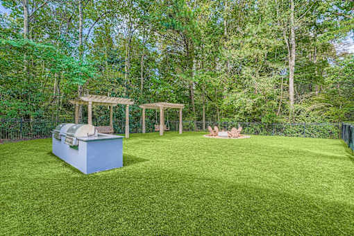 A backyard with a grill and a gazebo.