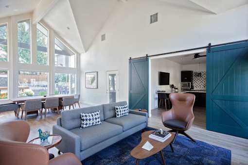A living room with a grey couch and brown chairs.