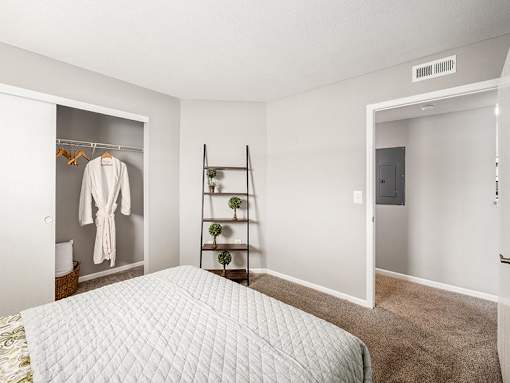 A bedroom with a bed, a closet, and a shelf.