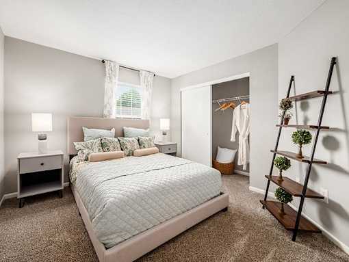 A bedroom with a large bed and a wooden ladder.