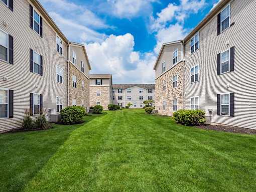 A grassy courtyard is surrounded by apartment buildings.