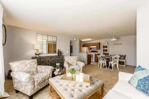 A living room with a white couch, a coffee table, and a dining table.