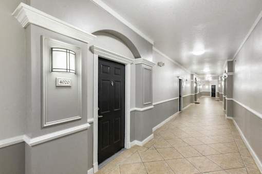 A hallway with a black door and a numbered plaque on the wall.