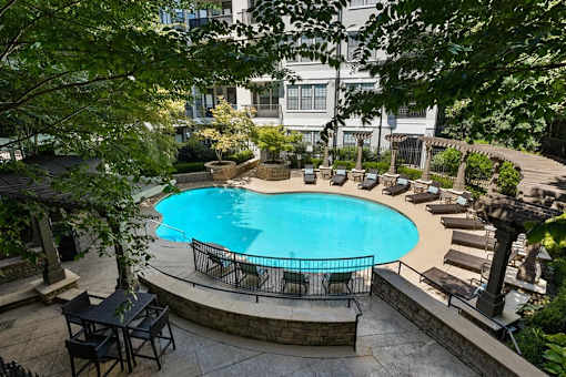 A small pool surrounded by a stone wall and patio furniture.