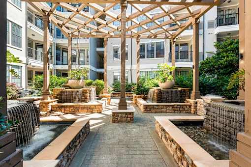 A courtyard with a fountain and a wooden pergola.