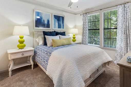 A bedroom with a bed, two lamps, and a window.