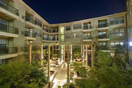 A building with a courtyard surrounded by trees at night.