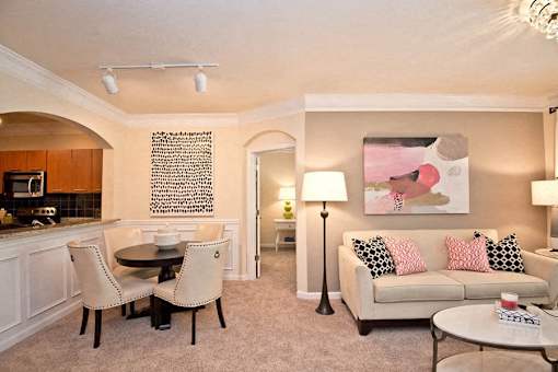 A living room with a couch, chairs, and a painting on the wall.