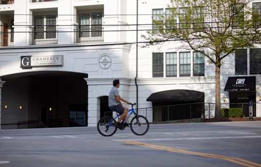 A man riding a bicycle in front of a building with a sign that says "Gramercy".