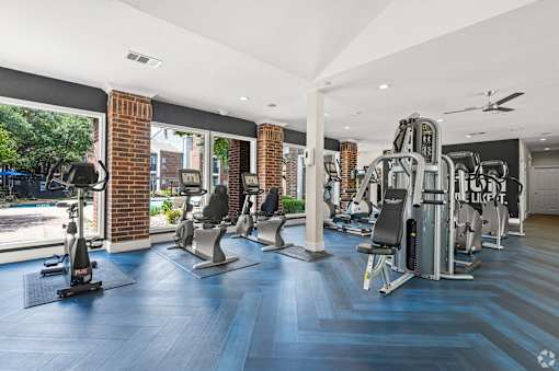 A gym with a variety of equipment including treadmills, weights, and a rowing machine.