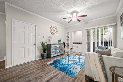 A living room with a white door, a blue rug, and a white couch.