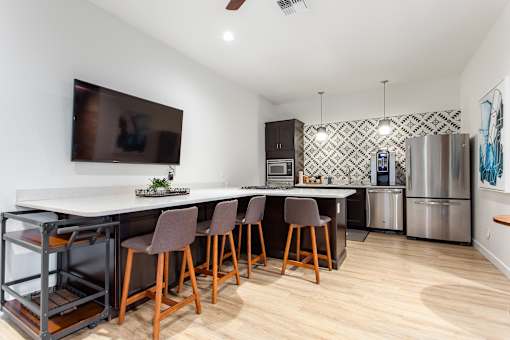 A kitchen with a white counter top and brown chairs.