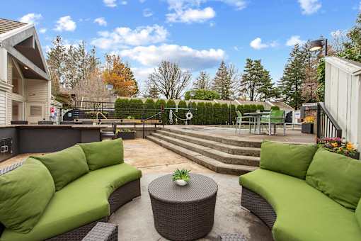 A patio with green couches and a table with a plant on it.