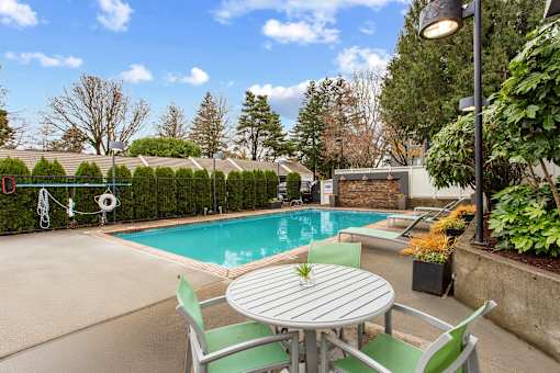 A table with a plant on it sits in front of a pool.