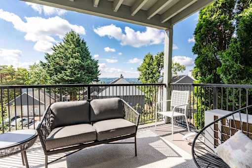A patio with a couch, chair, and table with a view of the mountains.