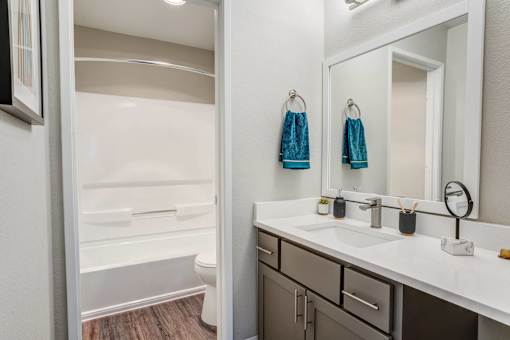 A bathroom with a white sink, a mirror, and a towel rack.