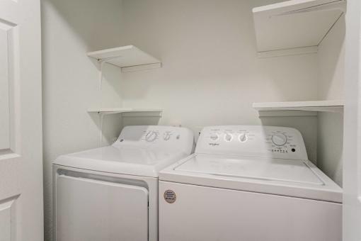 Two white washing machines in a small laundry room.
