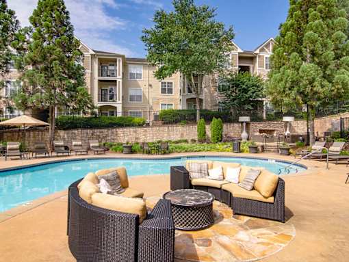 A poolside patio with a couch and a table.