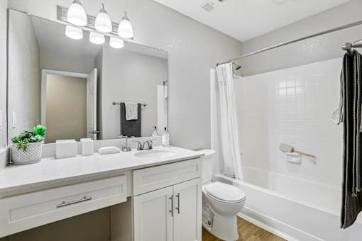 A white bathroom with a toilet, sink, and mirror.
