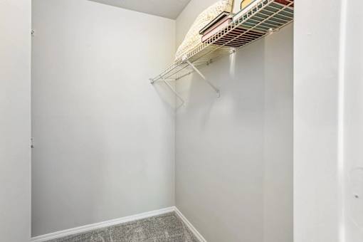 A white closet with a shelf and a fan.
