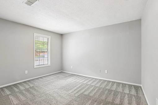 A room with a window and carpeted floor.