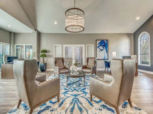 A living room with a large rug and a chandelier.