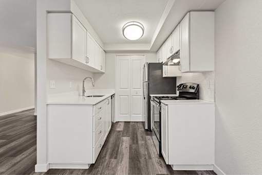 A modern kitchen with white cabinets and dark wood floors.