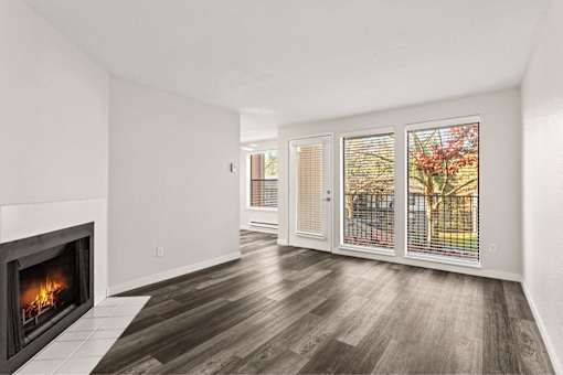 A room with a fireplace and a view of a tree outside.