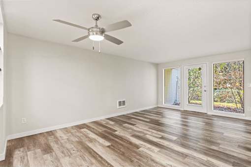 A room with a ceiling fan and wood flooring.