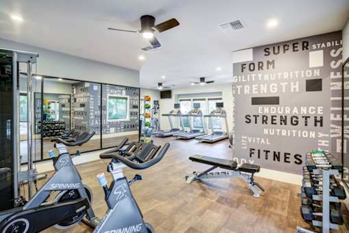 A gym with a row of stationary bikes and a wall of motivational words.