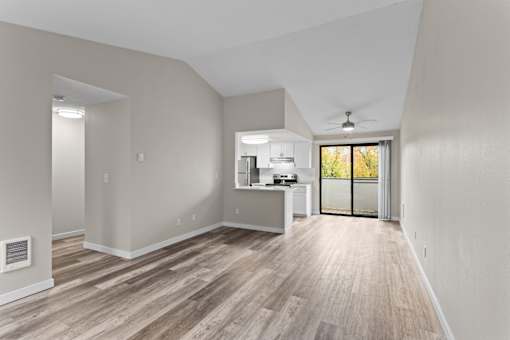 A spacious room with a kitchen area and a ceiling fan.