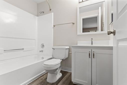 A white toilet sits in a bathroom next to a white bathtub.