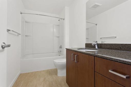 A white toilet sits in a bathroom with a sink and a shower.