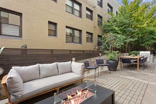 A patio with a couch, chairs, and a fire pit.