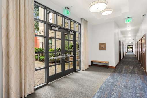 A hallway with a blue carpet and a glass door leading outside.