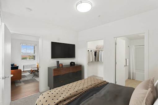 A bedroom with a bed, a television, and a window.
