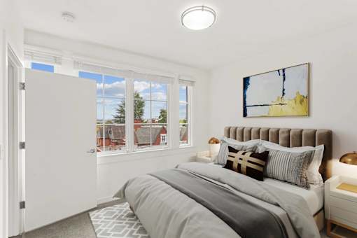 A bedroom with a large bed and a window overlooking a residential area.