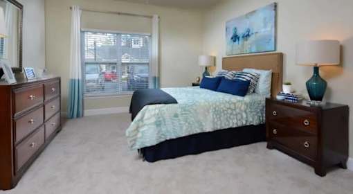 A bedroom with a bed, nightstand, and a painting on the wall.