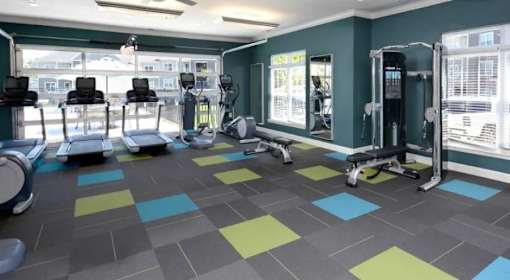 A gym with a variety of equipment including treadmills, weights, and exercise machines.