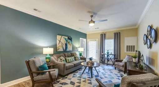 A living room with a couch, chairs, and a rug.