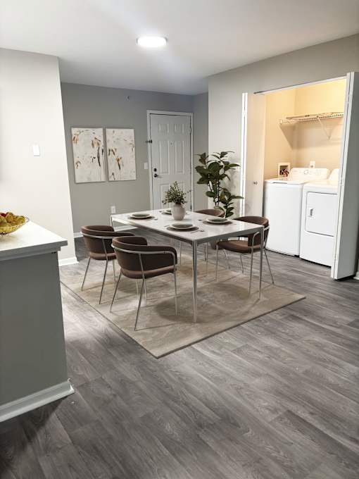 A dining room with a table set for four and chairs around it.