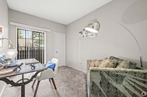 A well-lit bedroom with a bed, a table, and a chair.