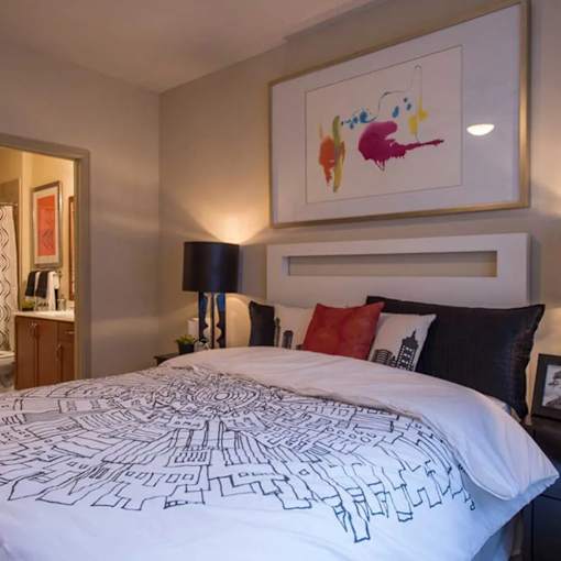 A bed with a white comforter with black outlines of buildings on it.