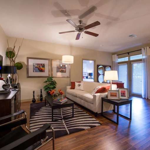 A living room with a white couch, a coffee table, and a ceiling fan.
