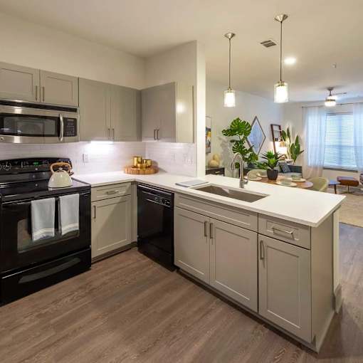 A modern kitchen with a black oven and wooden flooring.